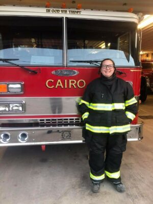 Female Cairo Volunteer Firefighter standing in front of truck